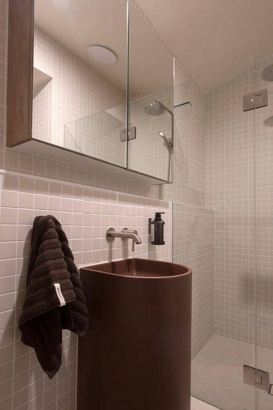 Chocolate home towel hanging in a tiled bathroom with stone basin