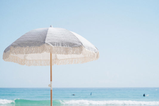 A large fringed beach umbrella creating shade beside the Australian coast.