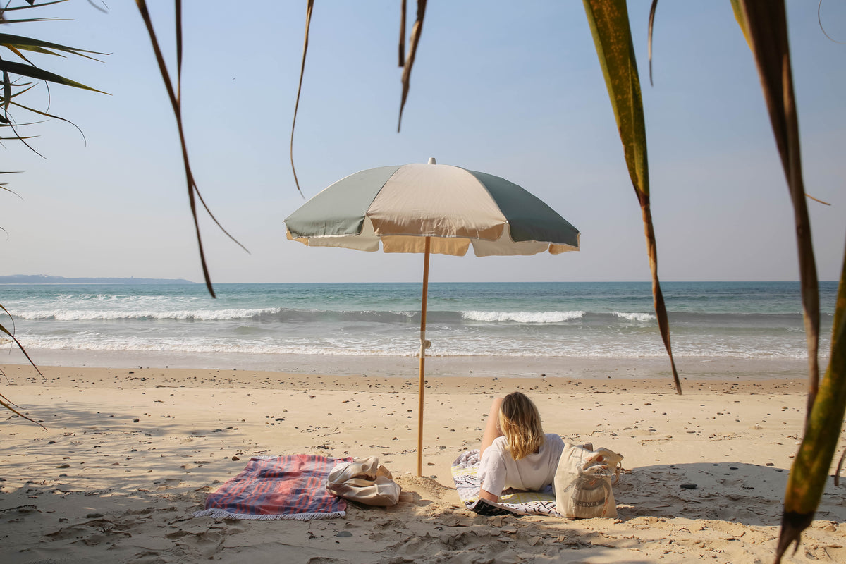 Relaxed beach scene beneath a Tallow Splice Beach Umbrella