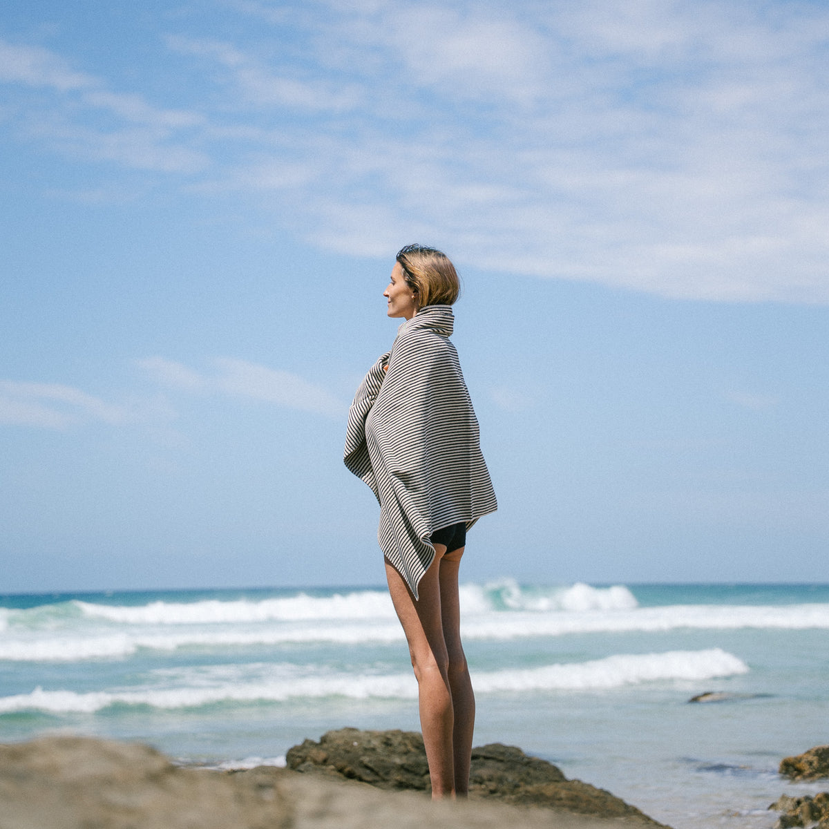 Side view of a model wrapped in a Black striped beach towel.